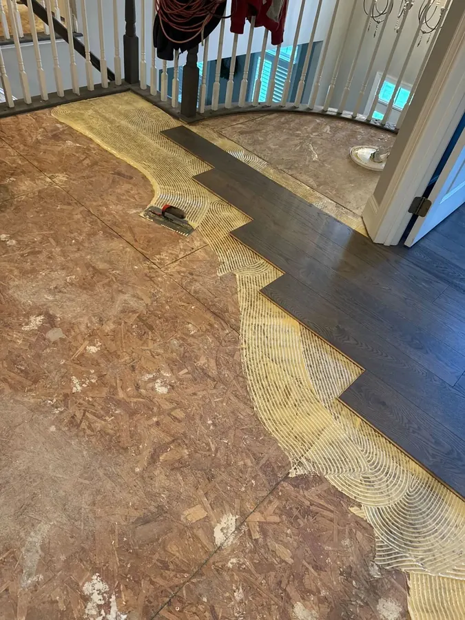 Glue down adhesive trowelled over the subfloor with the first dark boards going in