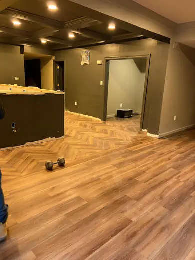 Wide plank LVP running into a herringbone section in a finished basement