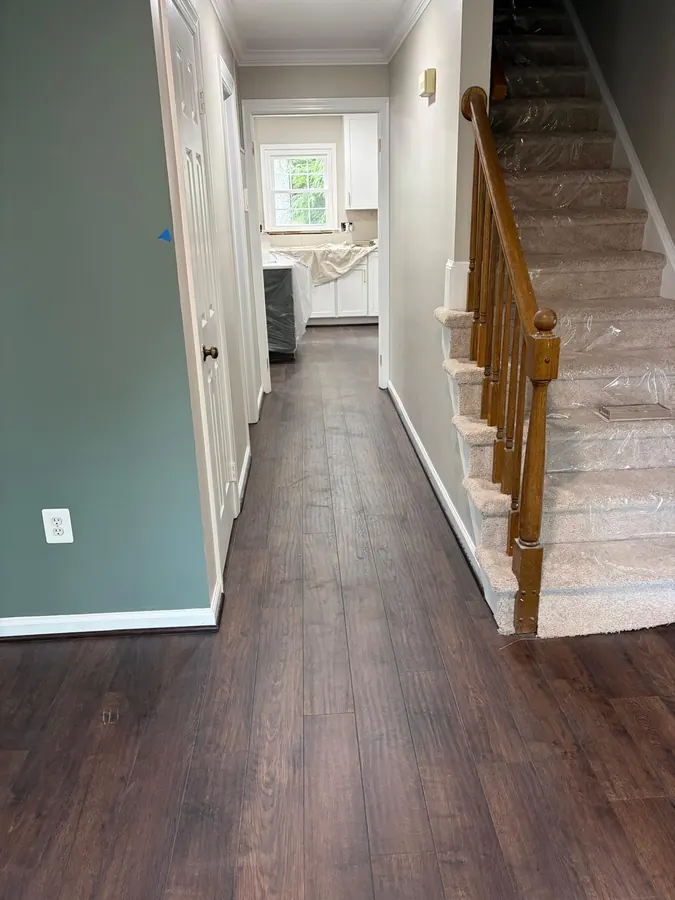 Dark LVP hallway beside a staircase with an oak handrail