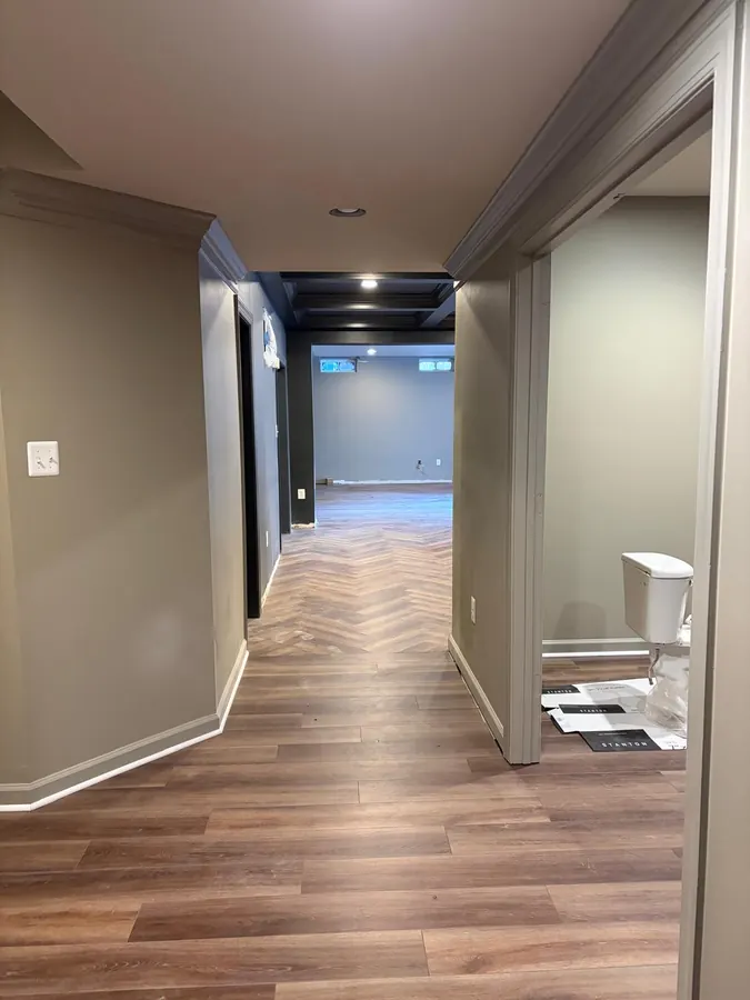 LVP hallway opening onto a herringbone laid floor