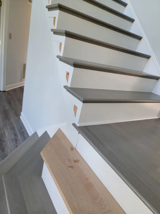 Grey stained stair treads going in over white risers