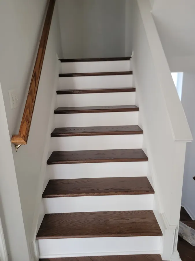 Walnut stained treads and white risers under an oak handrail