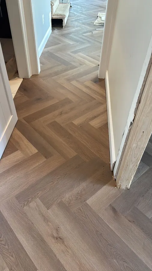 Greige herringbone running through a doorway into the next room