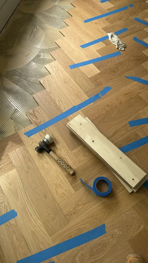 Oak herringbone going down, tape and a tapping block holding the run true