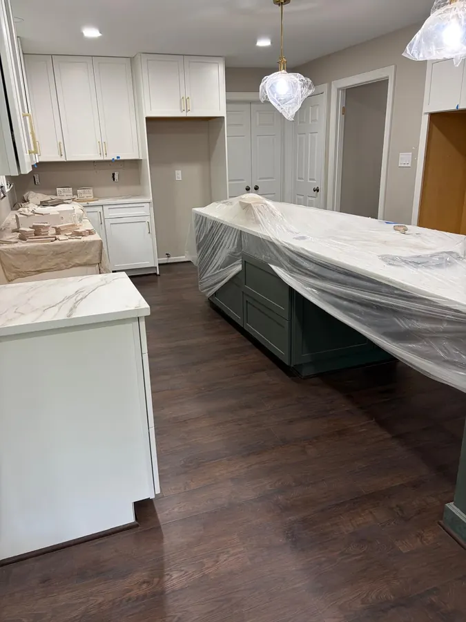 Dark plank flooring around a kitchen island with a marble top