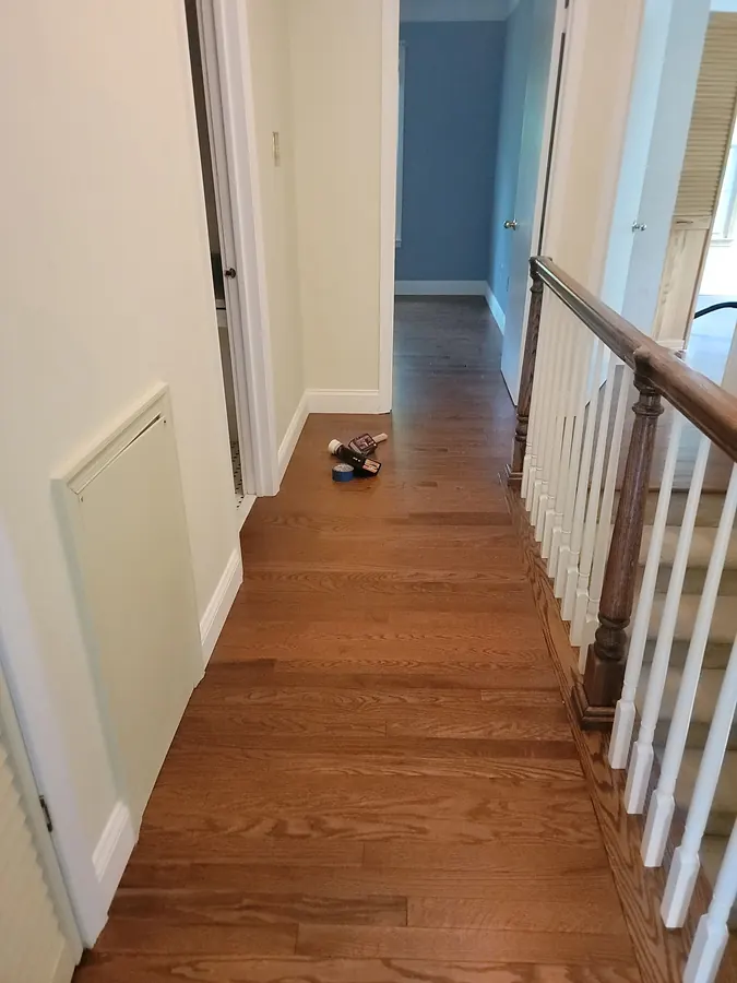 Red oak flooring across an upstairs landing beside white balusters